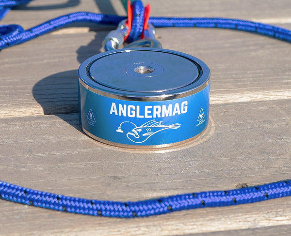 AnglerMag Dual-Sided Neodymium Fishing Magnet: Features top and side threaded mounting holes for vertical or horizontal dragging - Professional 1200lb pull force magnet on a wood dock with heavy-duty rope.